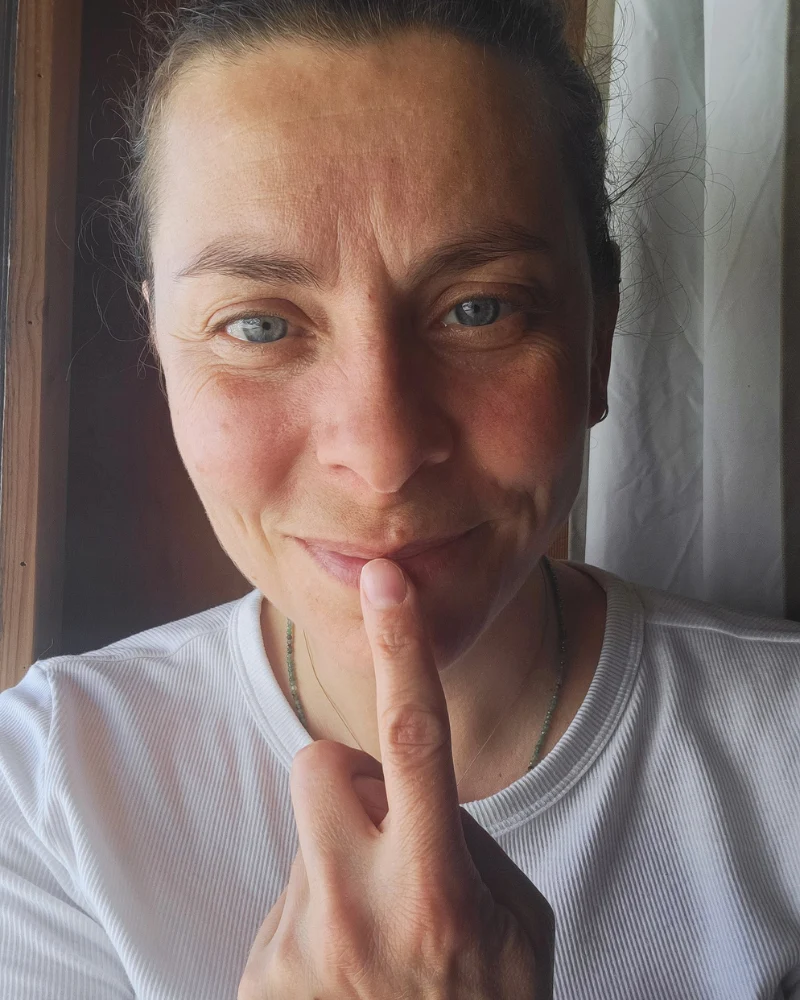 Elise, le doigt devant la bouche, complice
